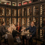 A group of people enjoying wine and food in the Library Room of Domaine Serene Wine Lounge in Lake Oswego