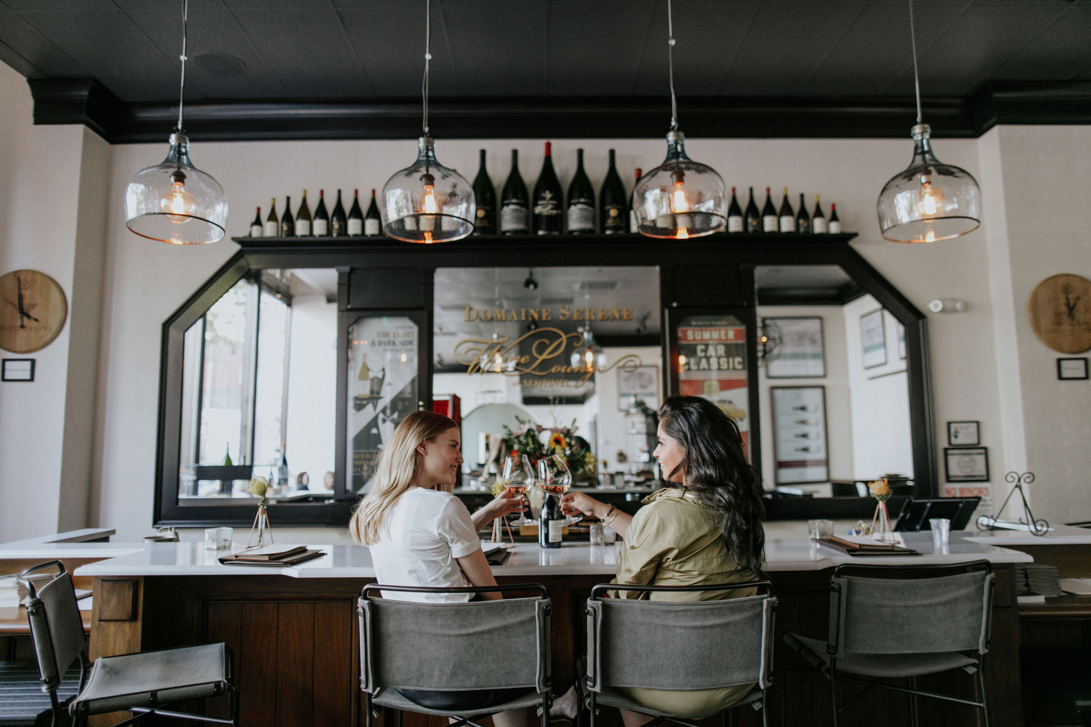 Two woman clinking wine glasses and enjoying a great day at Domaine Serene Wine Lounge