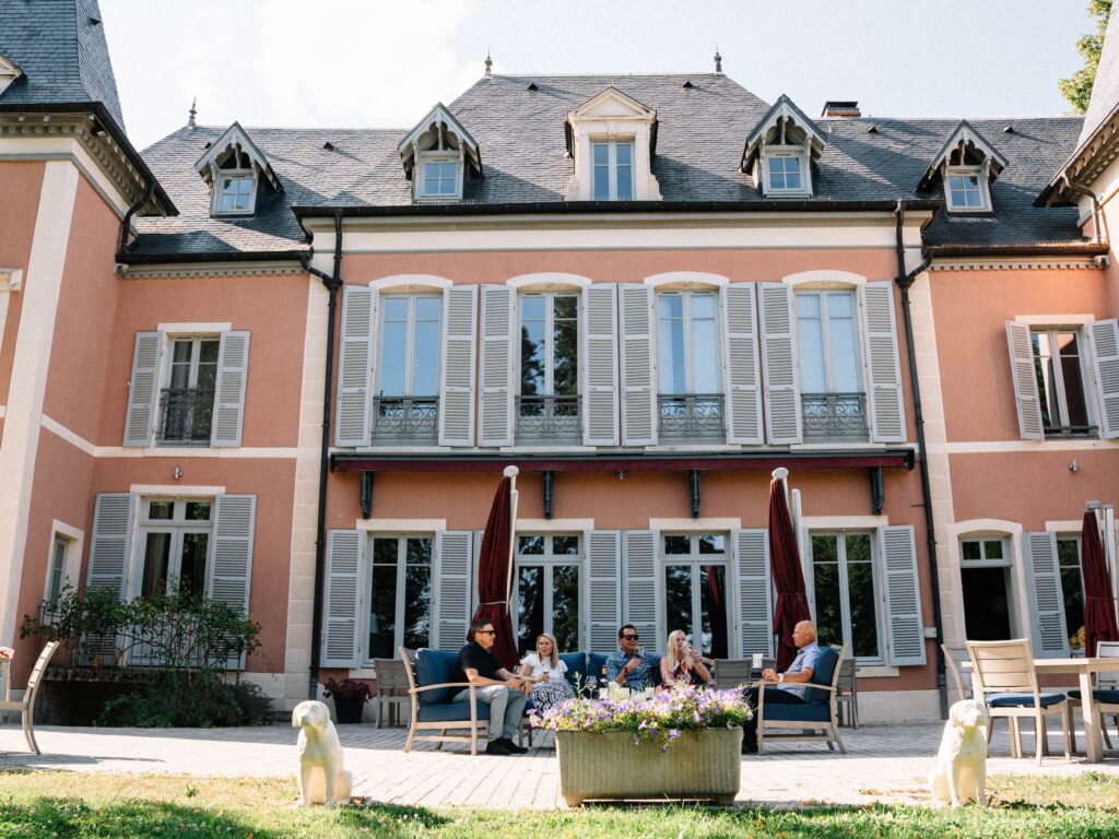 A group of friends sitting outside of the pink Château de la Crée in Santenay, France while sipping wine.